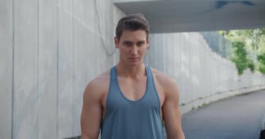 Yakışıklı, güçlü bir gencin portresi. Sağlıklı atletik fitness modeli kameraya bakıyor, dışarıda stadyumda duruyor.. 