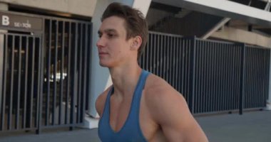 Dışarıda koşan yakışıklı bir sporcu. Stadyumda koşan adamın portresi. Gün batımında dışarıda spor yapıyorum. Atletik eğitim koşusu egzersizi