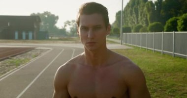 Yakışıklı, güçlü bir adamın portresi. Stadyumda poz veren sağlıklı atletizm modelleri. 