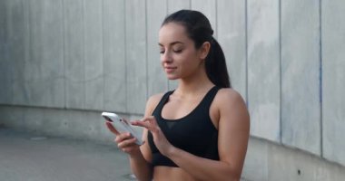 Koşudan sonra dışarıda cep telefonu kullanan genç bir bayan. Spor kadını portresi stadyumda telefonda sonuçları kontrol ediyor. Spor salonundaki kadın antrenmandan sonra akıllı telefona bakıyor.