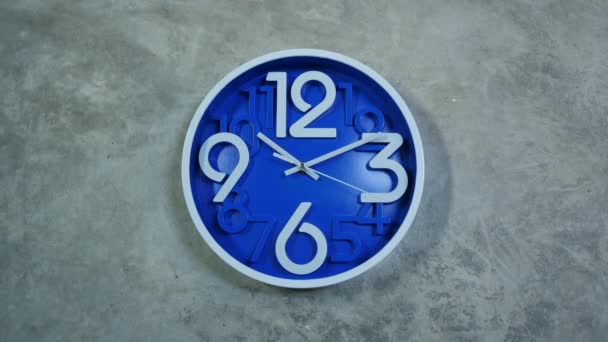 A blue office clock hangs on a gray concrete wall. Time lapse — Stock Video