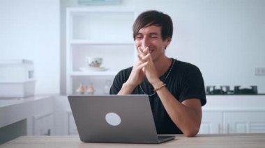 Gülümseyen adam iyi haberler okuyor ya da evde bilgisayarla komik videolar izliyor. Genç erkek, iyi haberlerle dolup taşan dizüstü bilgisayar monitörüne bakıyor. Merkez Ofis. 