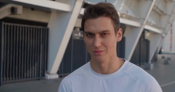 Retrato de um homem desportivo confiante a olhar para a câmara de manhã no estádio. Close-up, atleta corredor ao ar livre. Motivação desportiva — Vídeo de Stock