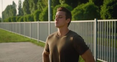 Formdan önce ısınan yakışıklı ve güçlü bir adamın portresi. Stadyumda poz veren sağlıklı atletizm modelleri..