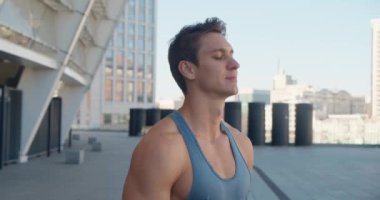 Yakışıklı, güçlü bir gencin portresi. Sağlıklı atletik fitness modeli kameraya bakıyor, dışarıda stadyumda duruyor.. 