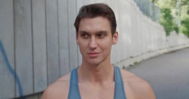 Yakışıklı, güçlü genç adamın yakın plan portresi. Sağlıklı atletizm modeli kameraya bakıyor ve gülümsüyor, stadyumda ayakta duruyor.. 