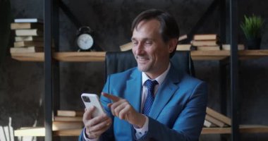 Profesyonel kıdemli iş adamı modern akıllı telefondan mesaj yolluyor. Patron modern cep telefonu teknolojisi uygulaması kullanıyor, iş yerinde e-posta yazıyor..