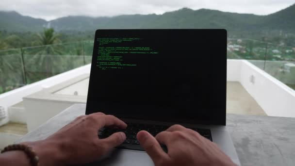 POV розробника-фрілансера пише зелений код в ноутбуці за межами офісу на рифі на фоні тропічних джунглів — стокове відео