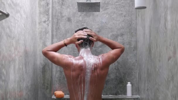 Vissza nézet Fiatalember Mosás és zuhanyozás zuhanyzóval Fürdő és mosás Samponnal a fürdőszobában Lassú mozgás. — Stock videók