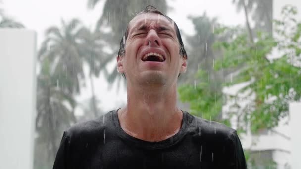 Портрет плачущего грустного человека, стоящего под проливным дождем и промокшего. Медленный выстрел — стоковое видео