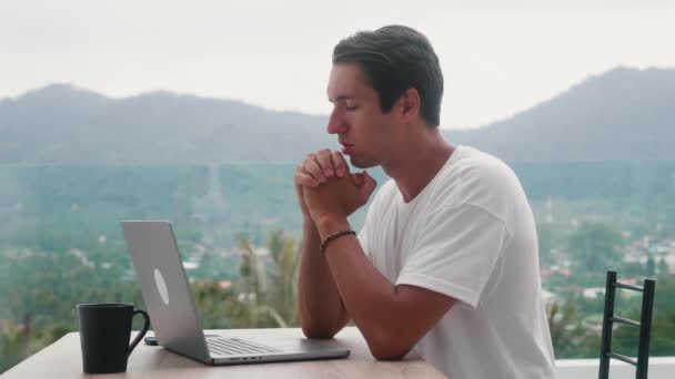 Sad man freelancer asking for help about problem, praying to God while working distantly with laptop computer. Religious male at table at home put hands in prayer. Guy praying with hope. — стокове відео