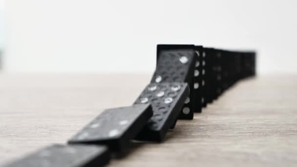 Domino effect in slow motion - falling black tiles with white dots. Dominoes falling in line effect business concept — Stockvideo