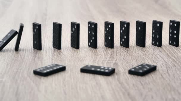Domino effect in slow motion - falling black tiles with white dots. Dominoes falling in line effect business concept — Wideo stockowe