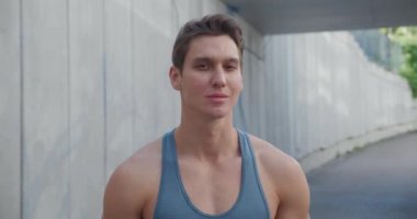 Yakışıklı, güçlü bir gencin portresi. Sağlıklı atletik fitness modeli kameraya bakıyor, dışarıda stadyumda duruyor.. 