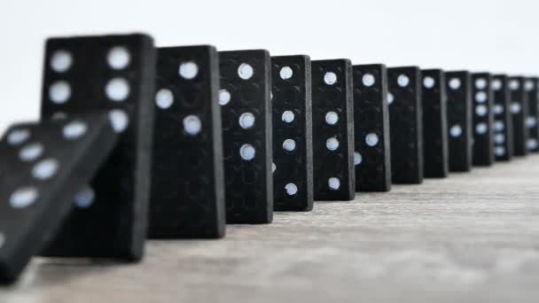 Domino effect in slow motion - falling black tiles with white dots. Dominoes falling in line effect business concept — Video