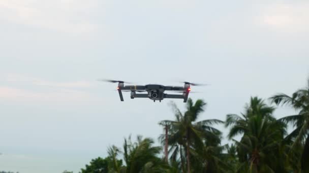 Квадрокоптерный дрон зависает и летит на фоне неба — стоковое видео