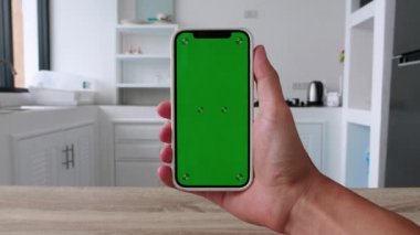 Yakın plan Adam, Mutfak Arkaplanındaki İnternet İçeriği Video Bloglarını İzleyen Yeşil Krom Ekran Anahtarı ile Telefon Kullanıyor. Yüksek kalite 4k görüntü