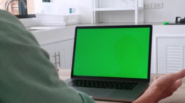 Yakın plan çekimde genç bir iş adamının evdeki yeşil renkli ekranlı dizüstü bilgisayarında görüntüsü var. Yüksek kalite 4k görüntü