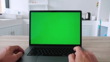 Yeşil ekranlı dizüstü bilgisayar. Erkek eller koşu pistinde yazı yazıp kaydırıyor. Mutfak masasında bilgisayar kullanan bir adam. Yüksek kalite 4k görüntü