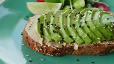 Yakın plan lezzetli avokado tostu ve tabakta salata. Susam ve keten tohumu. Vejetaryen yemeği. Yüksek kalite 4k görüntü
