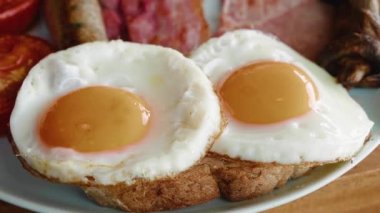 Close-up fried eggs on toasts. English breakfast on white plate. High quality 4k footage