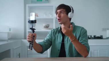 Kablosuz kulaklıklı bir adam cep telefonuyla bir video görüşmesinde konuşuyor. Popüler bir blogcu evinde, akıllı telefonunu kullanarak internet için bir video blogu kaydediyor.