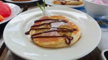 Börek. Çikolata soslu krepler, bir kepçe dondurmayla beyaz tabakta servis ediliyor. Yakın plan. Döndürme atışı.