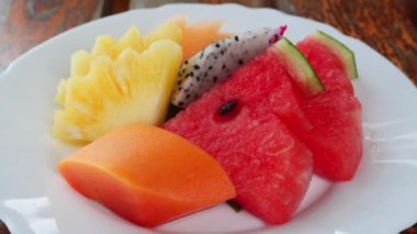 Close up. Colorful arrangement of assorted tropical fruits on a white plate. Raw vegan and healthy food. Restaurant menu
