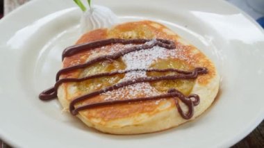 Close-up of pancakes poured with chocolate sauce, serving on a white plate with a scoop of ice cream. Pancakes Day