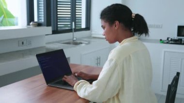 Rear view of a hardworking woman using laptop with copy ad space on a blank screen, studying remotely from home office
