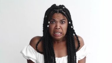 Scared woman covers her eyes with hands, feeling horror and fright, peers into camera with curiosity through her fingers