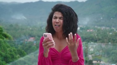 Emotional portrait of an African young pretty woman, disappointed by the news received on her smartphone.