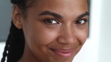 Seductive young African woman mysteriously looks away and smiles sweetly with a beautiful toothy while looking at camera