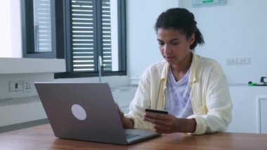 Pretty woman transfers the data from credit card into laptop while making online payments or shopping in internet store