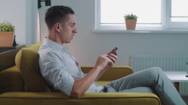 Kazanan genç adamın akıllı telefonu olması sürpriz oldu. İyi haberler okudu. Evdeki mobil online bahis oyunundan çok etkilendi. Mutlu erkek, koltukta otururken zaferin verdiği sevinçle cep telefonu ekranına bakar..