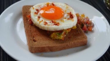 Round shaped roasted egg with raw vegetables on a whole grain bread on a white plate. Appetizer. Snack. Restaurant menu