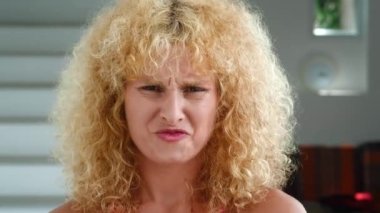 Disgusted young woman with curly hair feeling aversion, frowning face, close-up portrait. High quality 4k footage