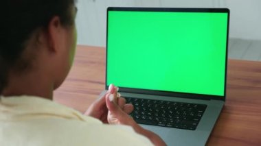 Focus on a laptop monitor green chromakey screen and the hands of a copywriter woman typing text on keyboard. Copy space