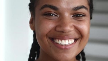 Headshot of pleasant young beautiful woman with stylish dreadlocks, smiling toothy smile, confidently looking at camera