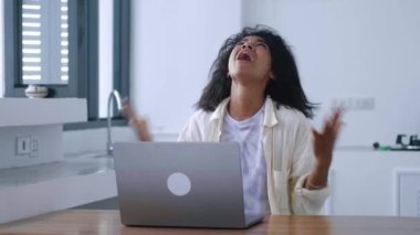 Multitasking woman feeling depressed while failing her planned project, during remote work on laptop in a home interior