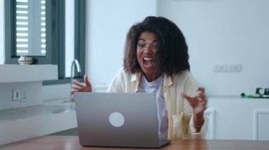 Beautiful overjoyed female entrepreneur, expressing happiness from goals achievement, while working on laptop from home