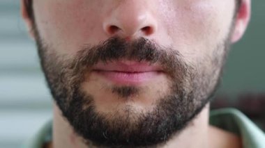 Tarafsız duyguları kameraya yansıyan yakışıklı sakallı bir adamın dudaklarına odaklan. Erkek güzellik portresi