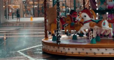 Yağmurlu bir günde lunaparkta atları taşıyan bir atlıkarıncaya odaklanın. Sağanak. Şehirde sağanak var.