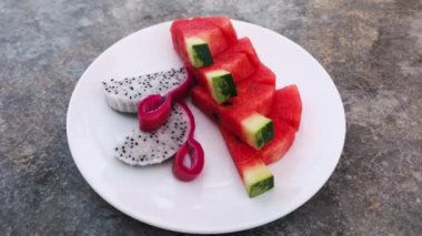 Beyaz tabakta servis edilen karpuz dilimleri ve ejderha meyveleri. Sağlıklı beslenme. Çiğ vejetaryen menüsü. Egzotik Meyveler