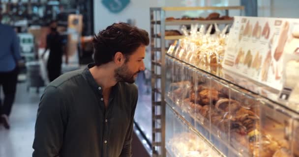 Hübscher Kerl Steht Vor Der Bäckereiabteilung Und Wählt Beim Einkaufen — Stockvideo