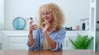 Beyaz saçlı çekici genç bir kadın akıllı telefonunda yazı yazıyor, web sitelerine bakıyor, internette geziniyor.