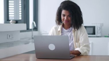 Online çalışmak için dizüstü bilgisayar kullanan çok görevli genç kız, klavyeye mesaj yazıyor, gülümsüyor.