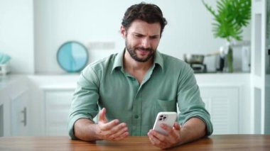 Koyu renk saçlı, beyaz sakallı, akıllı telefon kullanıcısı, bozuk telefonu azarlıyor ve kötü amaçlı yazılım tespit ediyor.