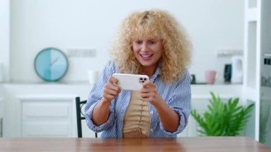 Akıllı telefondan bilgisayar oyunu oynayan heyecanlı, güzel bir kızıl kadın. Dijital alet bağımlılığı. Eğlence. Boş zaman.