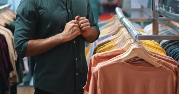 在服装店里购物的一个时尚迷人的高加索人的剪影 检查T恤衫的质量 — 图库视频影像